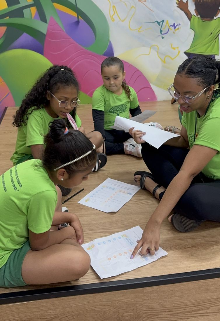 Educadora do Instituto Ebenézer em atividade de leitura com crianças sentadas no chão